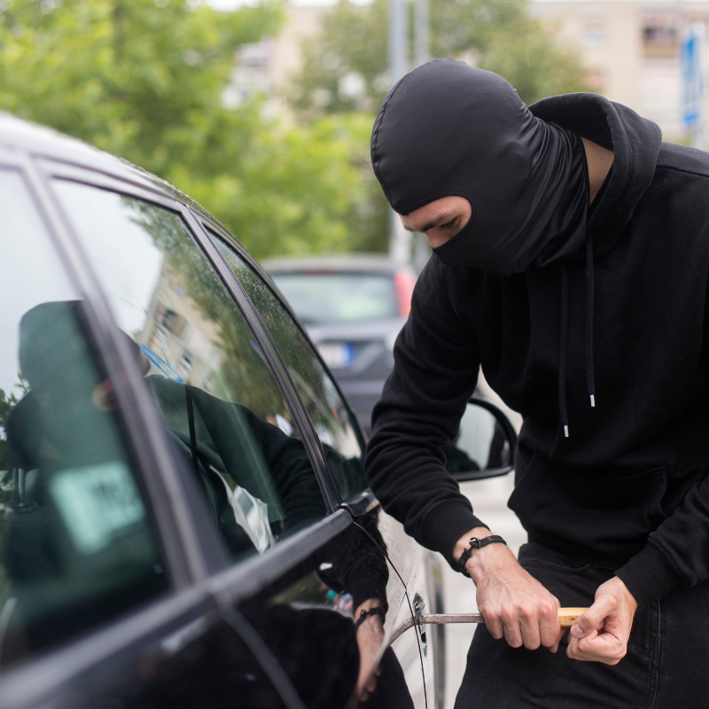 Car being tampered with by a thief, representing vehicle break-in damage that Core Collision Kyle - Buda and Georgetown locations repair.