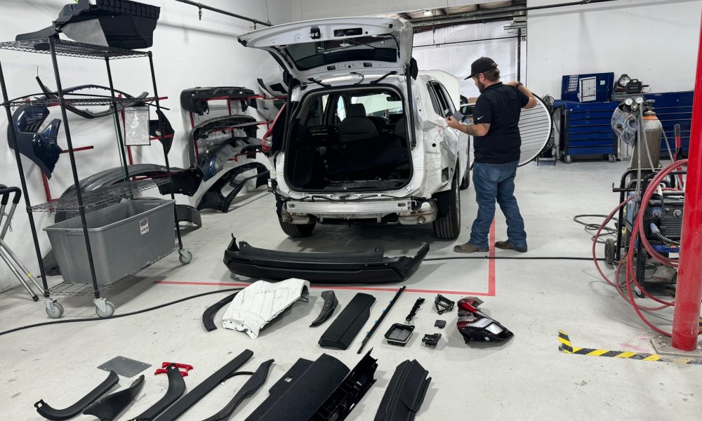 Core Collision Georgetown technician performing a full damage assessment for collision repair, with removed bumpers and components organized around the workspace.