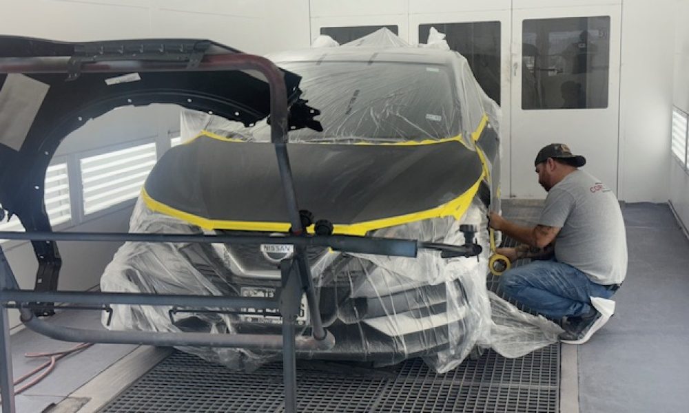 Close-up view of a Core Collision Georgetown technician masking a vehicle in the paint booth for precision refinishing and collision repair.