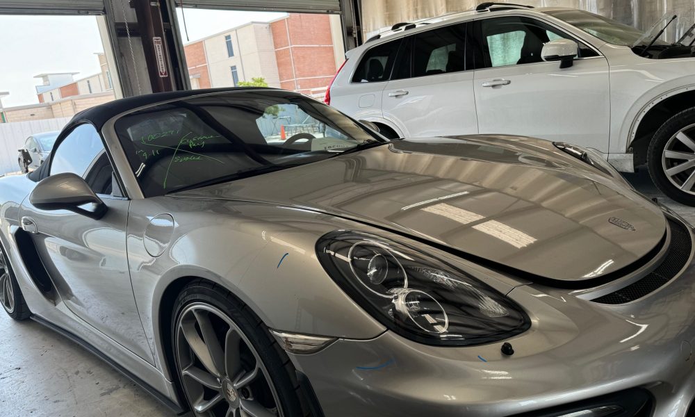 Silver Porsche convertible inside the Core Collision Kyle Buda repair shop, showing precision auto body repair work on luxury vehicles in Kyle Texas