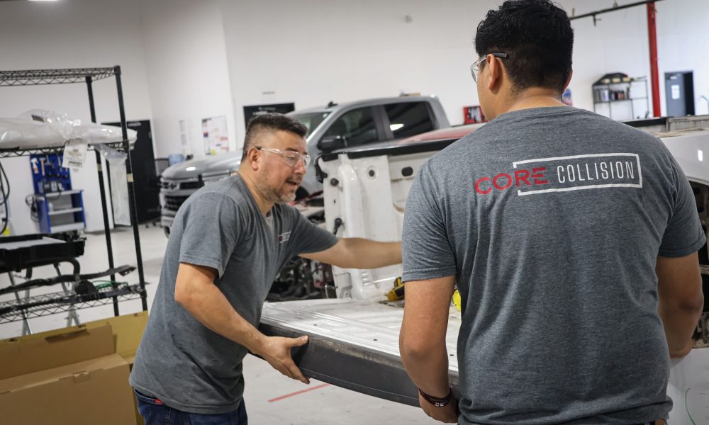 Two Core Collision technicians work together to install a truck tailgate during a collision repair at Core Collision in Georgetown, TX.