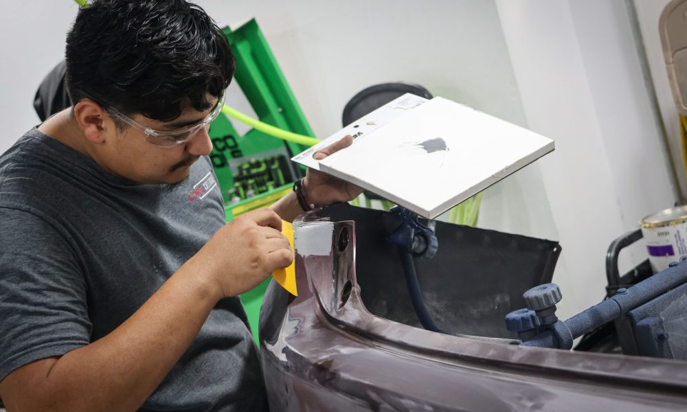 A Core Collision technician carefully inspects and sands a vehicle body panel before refinishing at the Georgetown, TX collision repair shop.