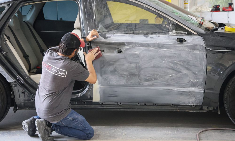 A Core Collision technician sands a vehicle door during the body repair process at the Georgetown, TX shop.