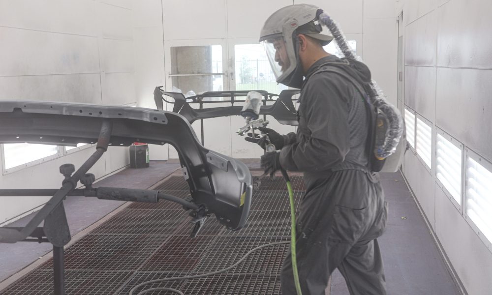 A Core Collision technician prepares to spray a vehicle body panel inside the paint booth during the refinishing process in Georgetown, TX.